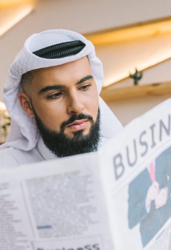 close-up shot of serious muslim businessman reading newspaper